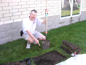 Pat, WA0TDA, points to a hole in the ground.