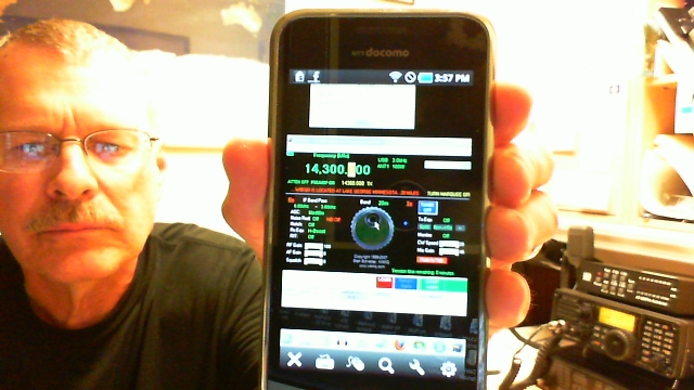 Pat, wa0tda, holds smartphone that controls radio in the background of the photo.