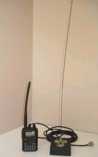 Yaesu HT and Larson quarter wave mag mount antenna side by side on a shelf.